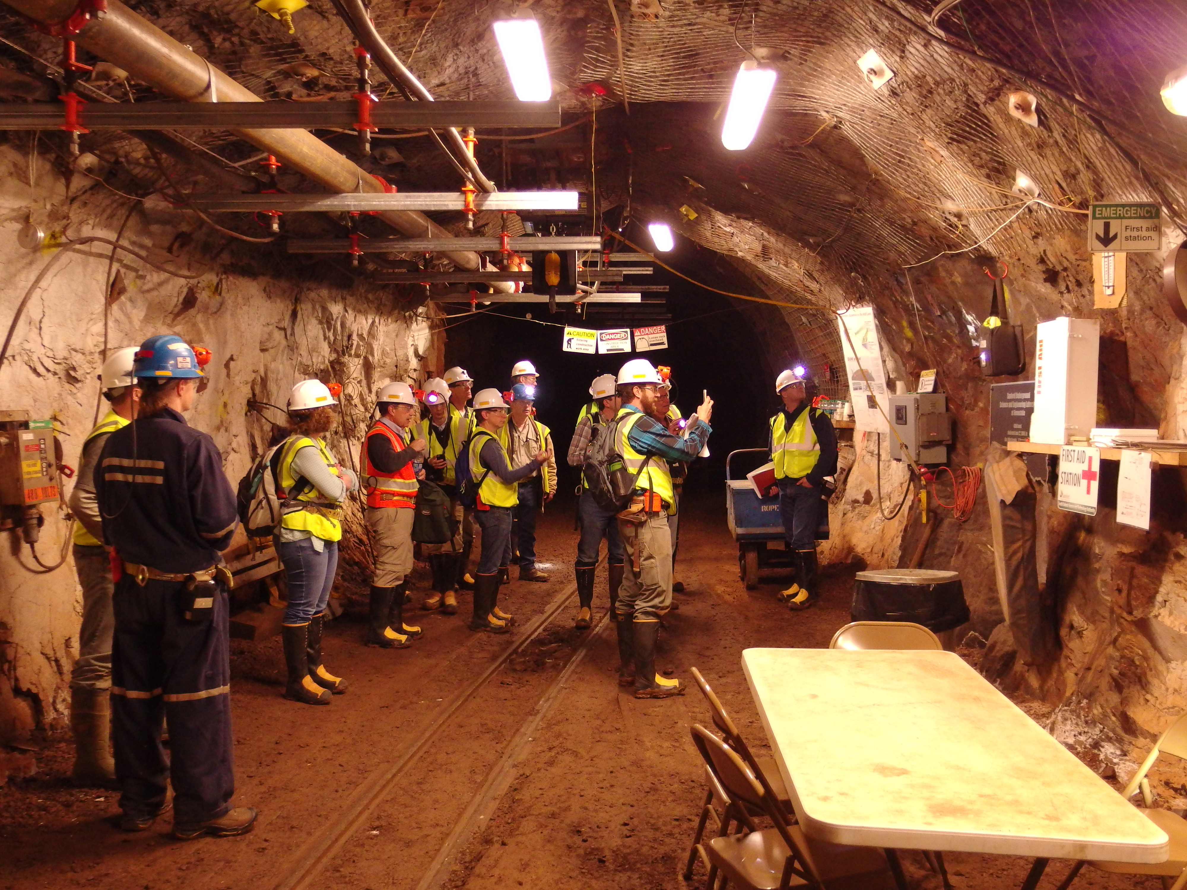 Photo of a group of workers in hard hats in an underground tunnel.