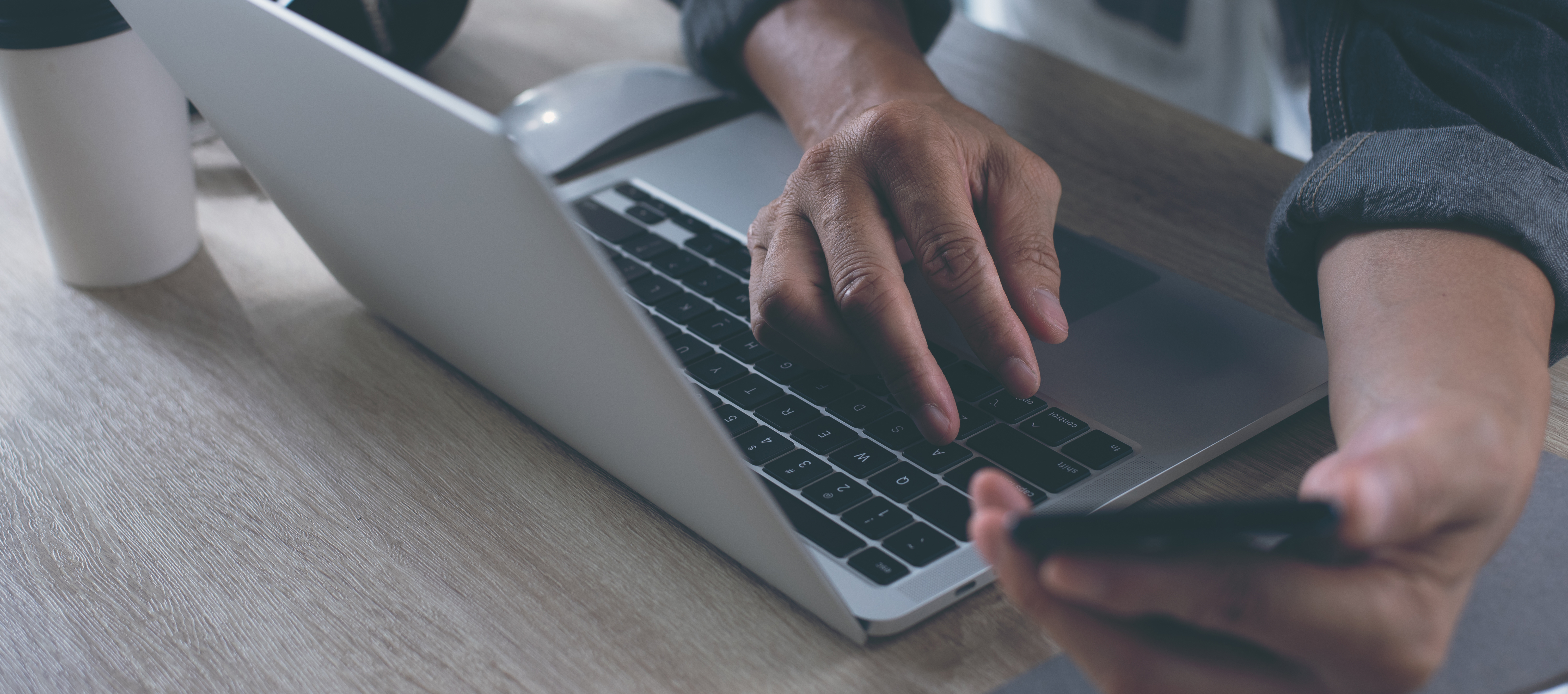 Person on computer holding phone