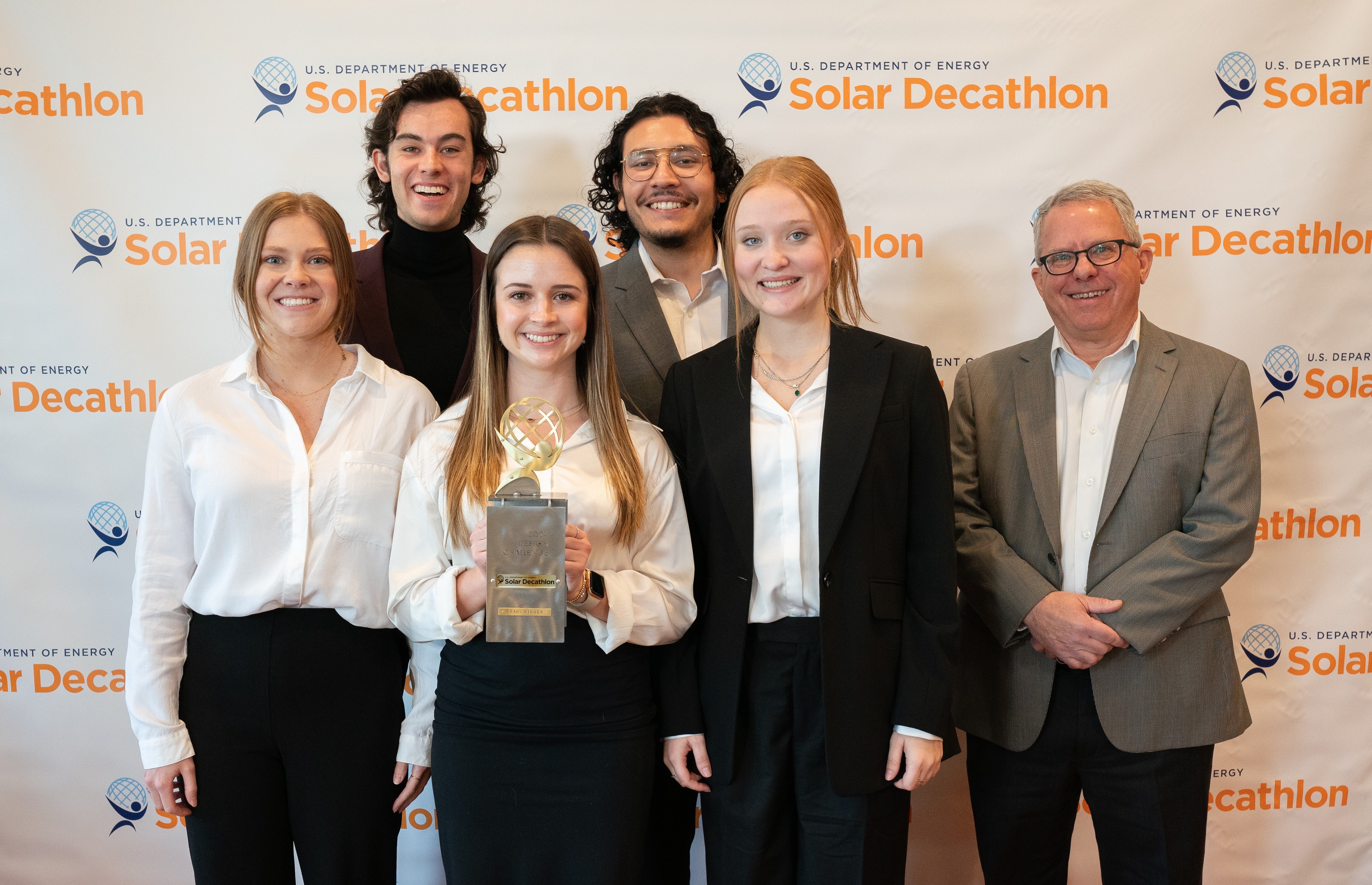 Photo of six people, one of whom is holding a trophy.