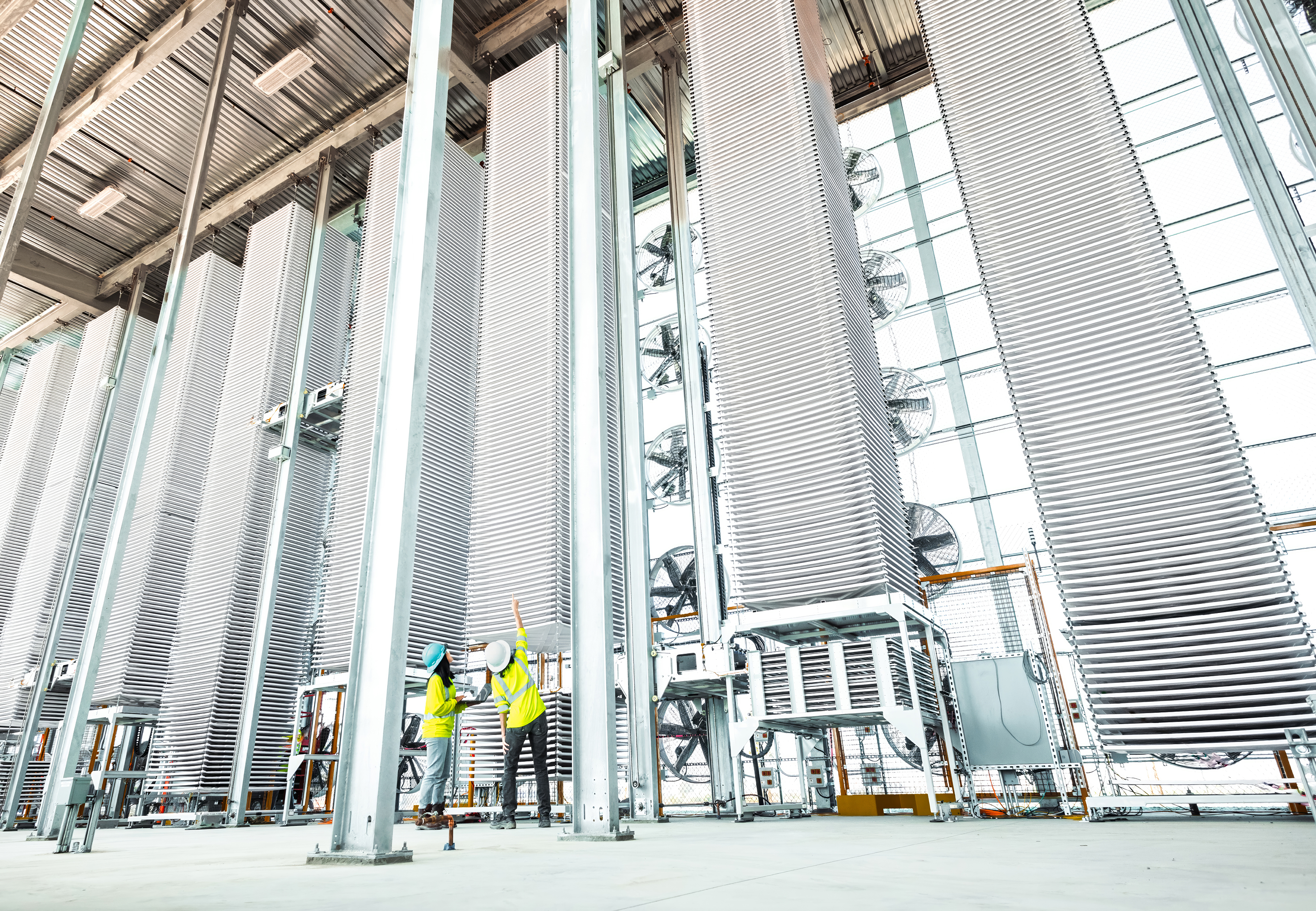 Two Heirloom technicians inspect a row of contactor towers in Heirloom’s commercial Direct Air Capture facility