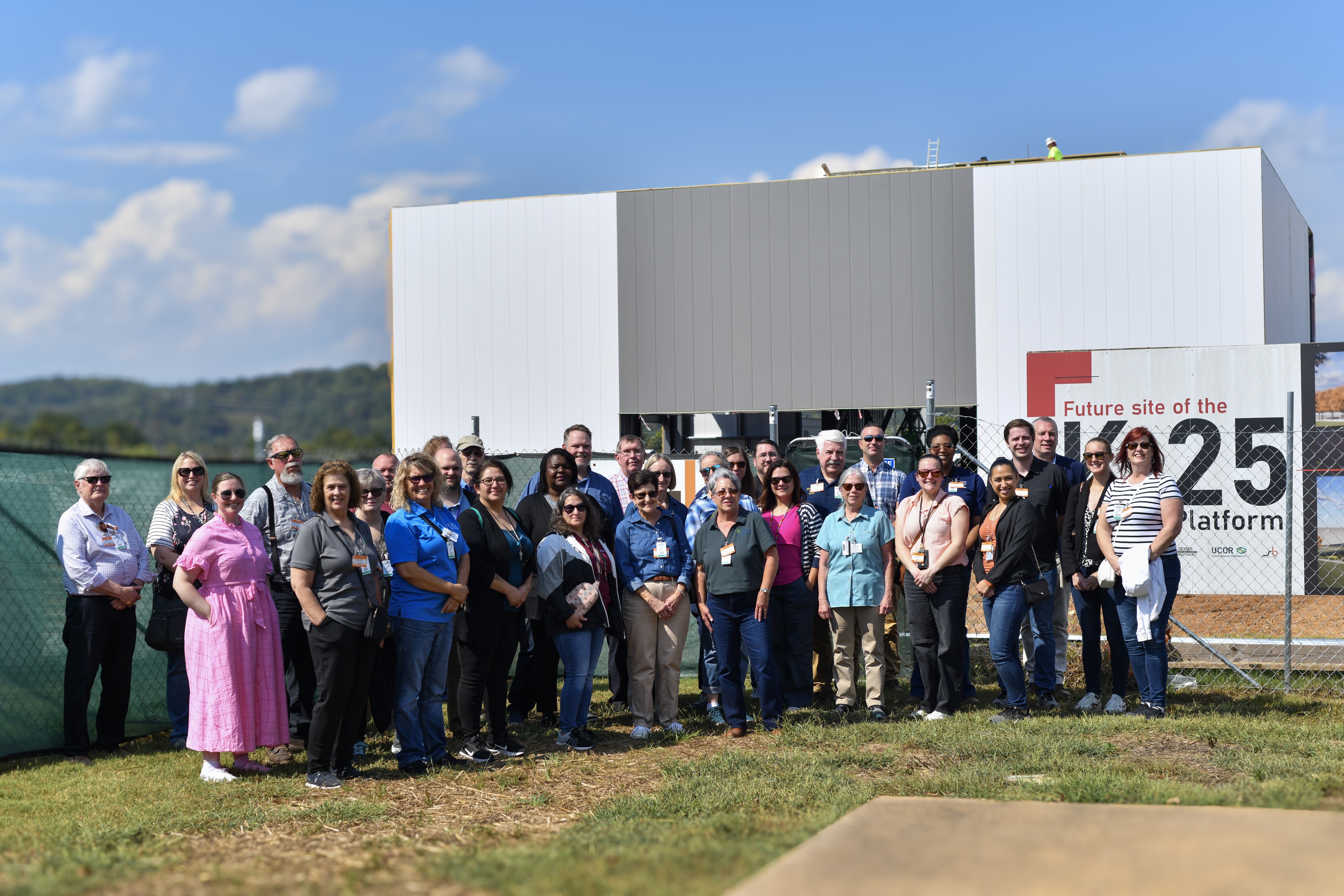 A group of people pose outside for a picture in front of a large white building