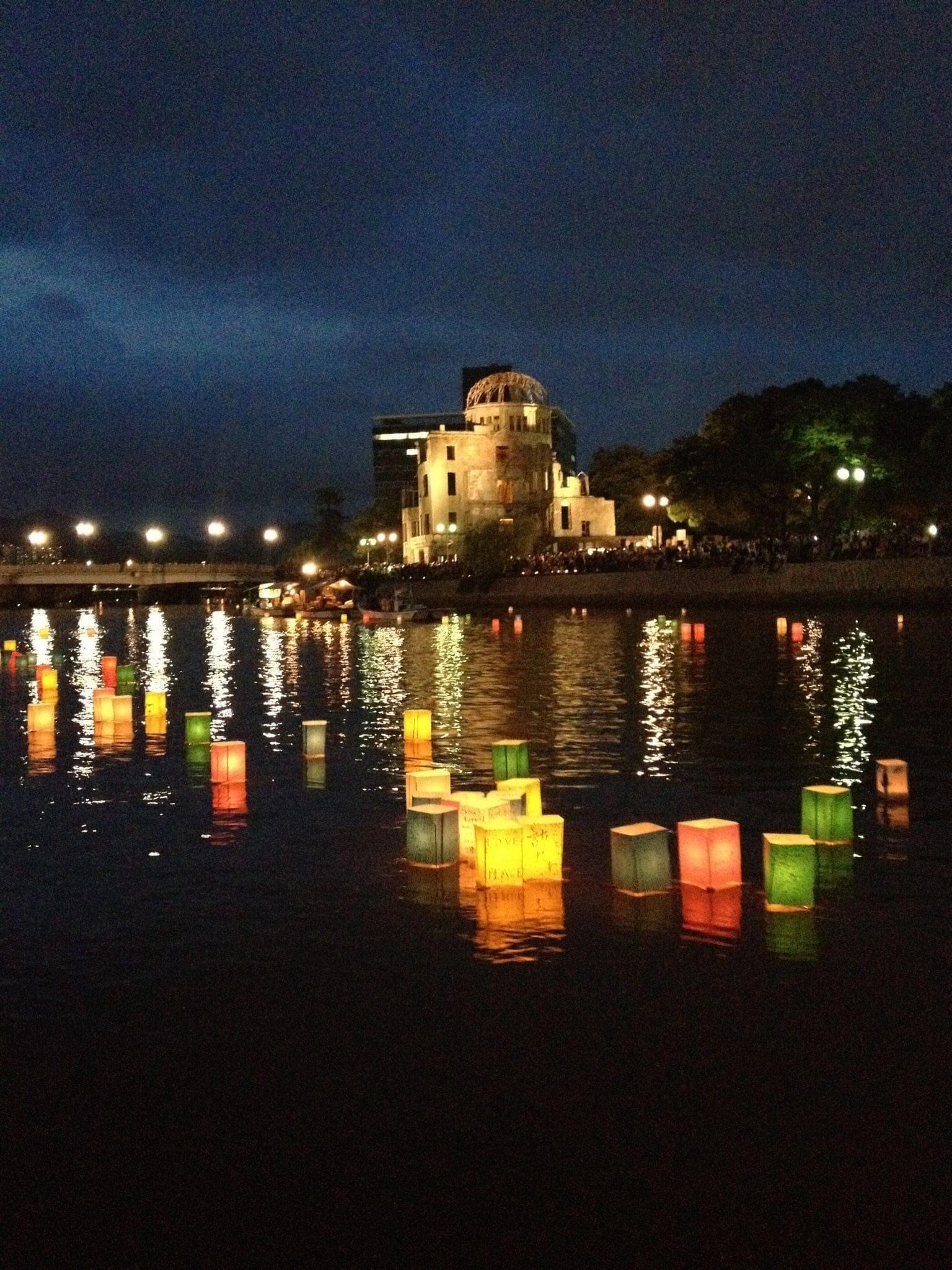 The Hiroshima Genbaku or "atomic bomb" dome behind lanterns floating down the Motoyasu River on Peace Memorial day.