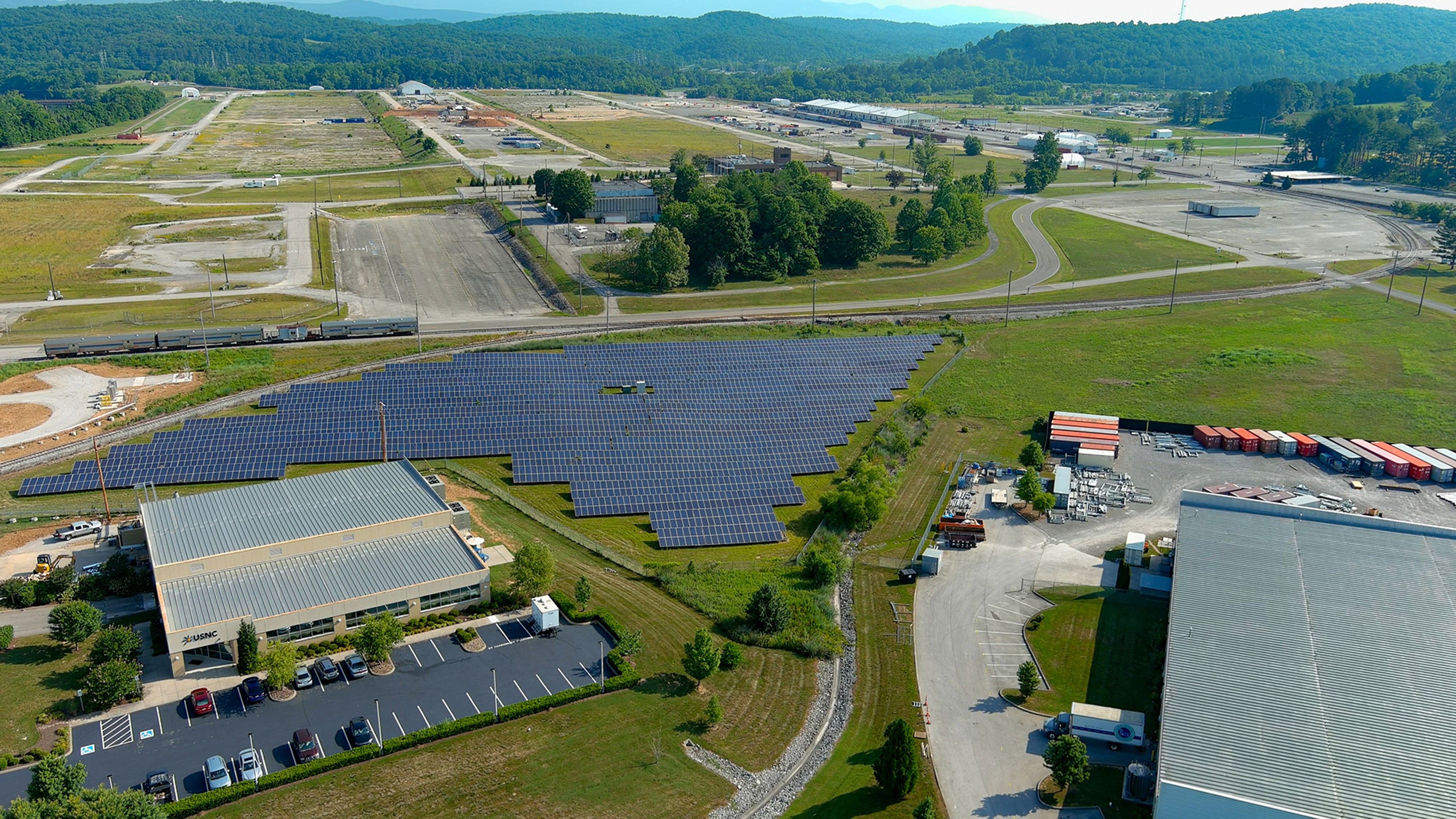 Airal photo of buildings and a large solar energy field. 