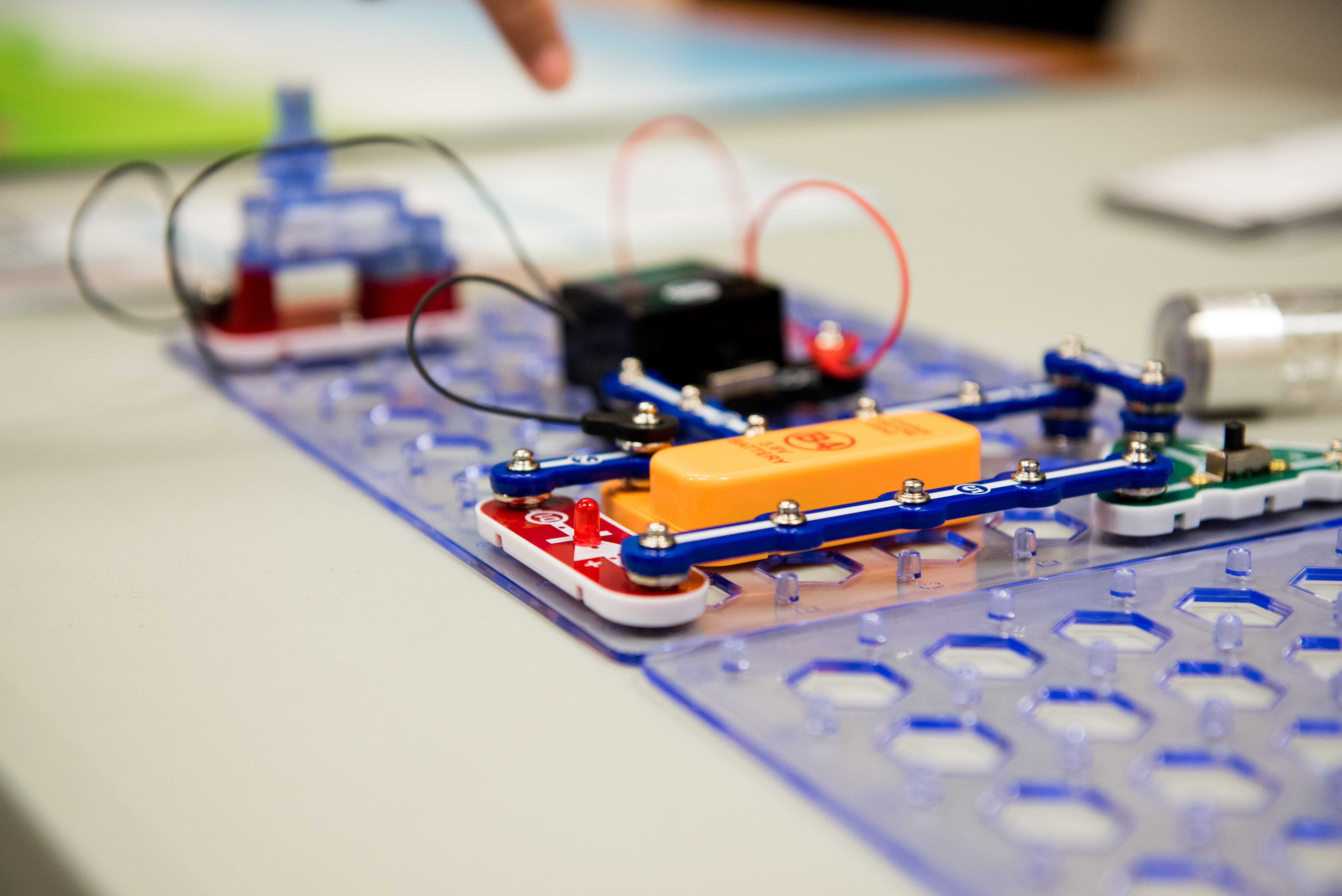 A small red breadboard with an orange module and red wires coming out of it