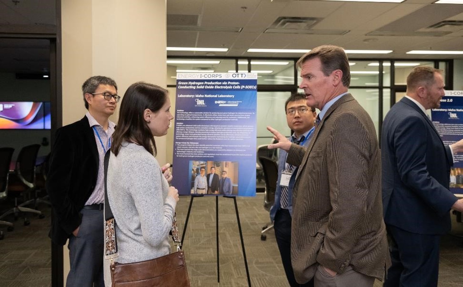 Four people converse around a blue informational poster on an easel.