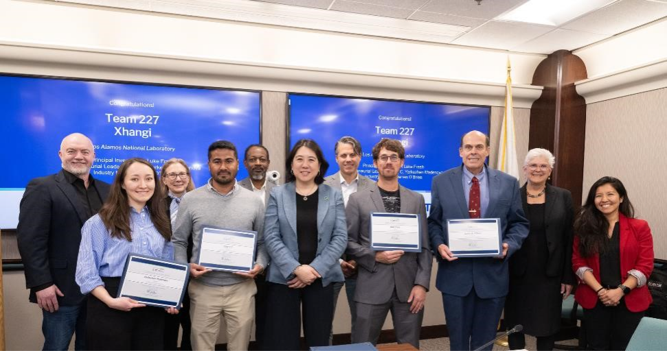 A group of 11 people pose and smile for the camera, with four holding certificates. 