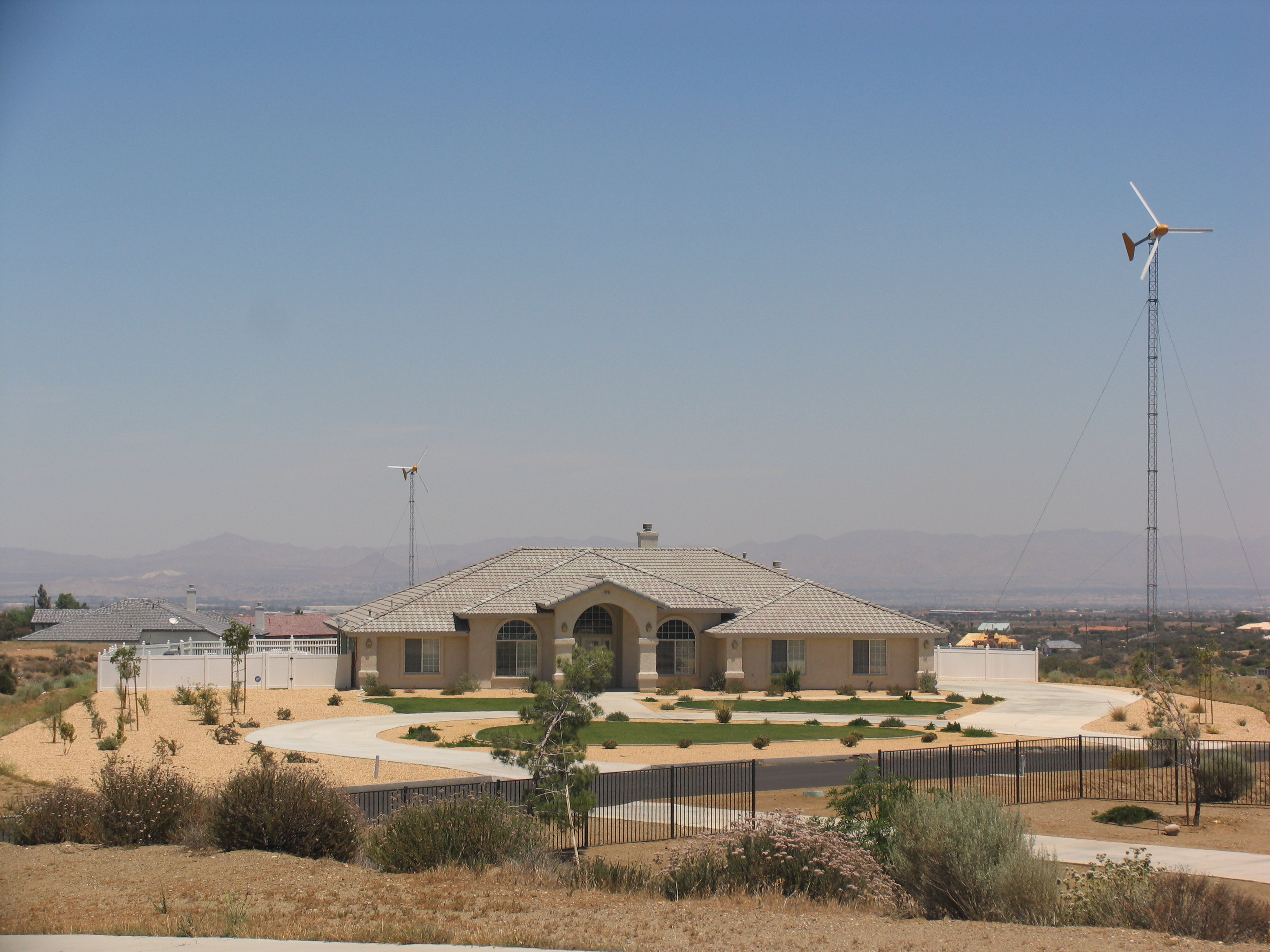 A building surrounded by grass and trees with a wind turbine next to it