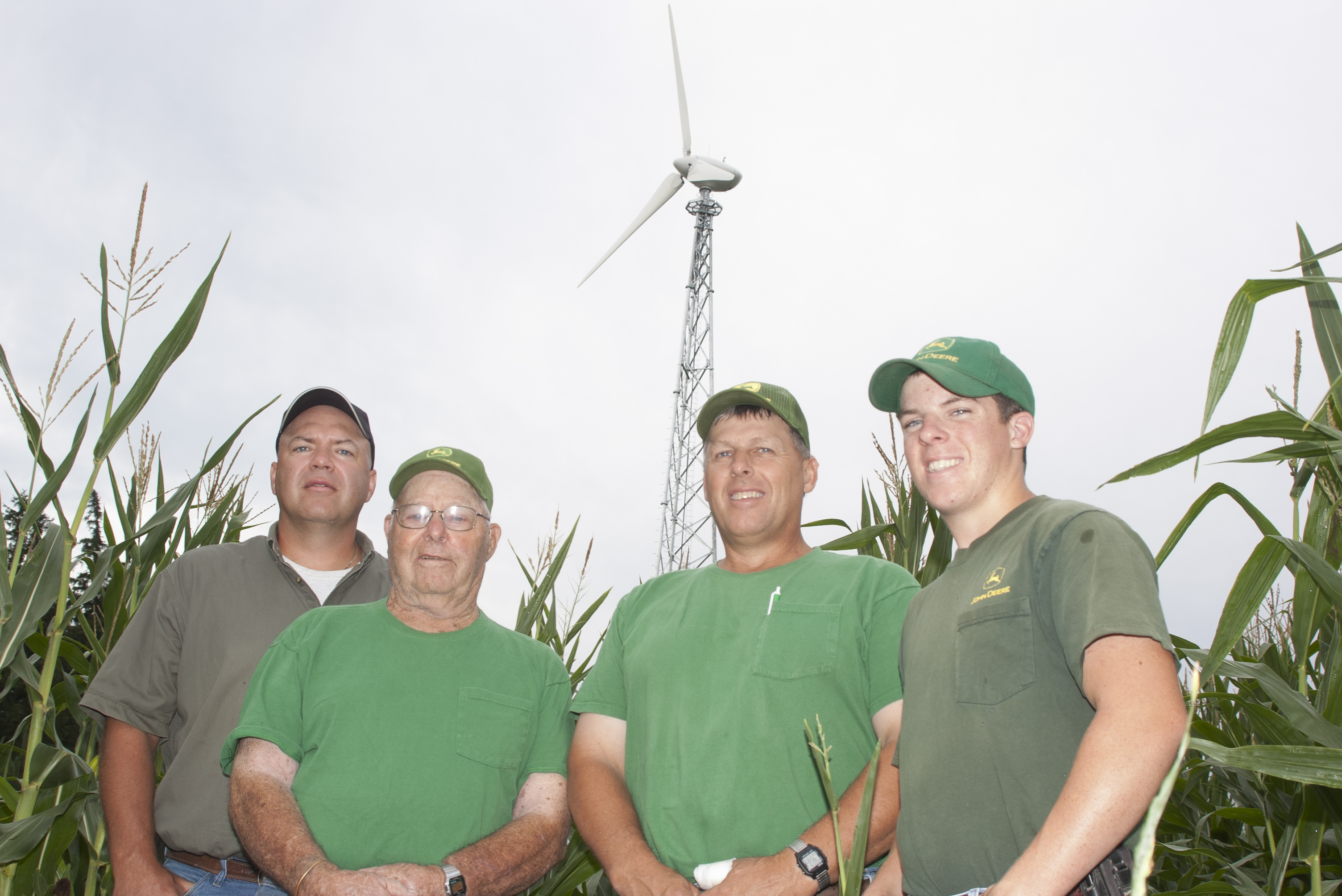 Farmers stand in the grass of a wind turbine