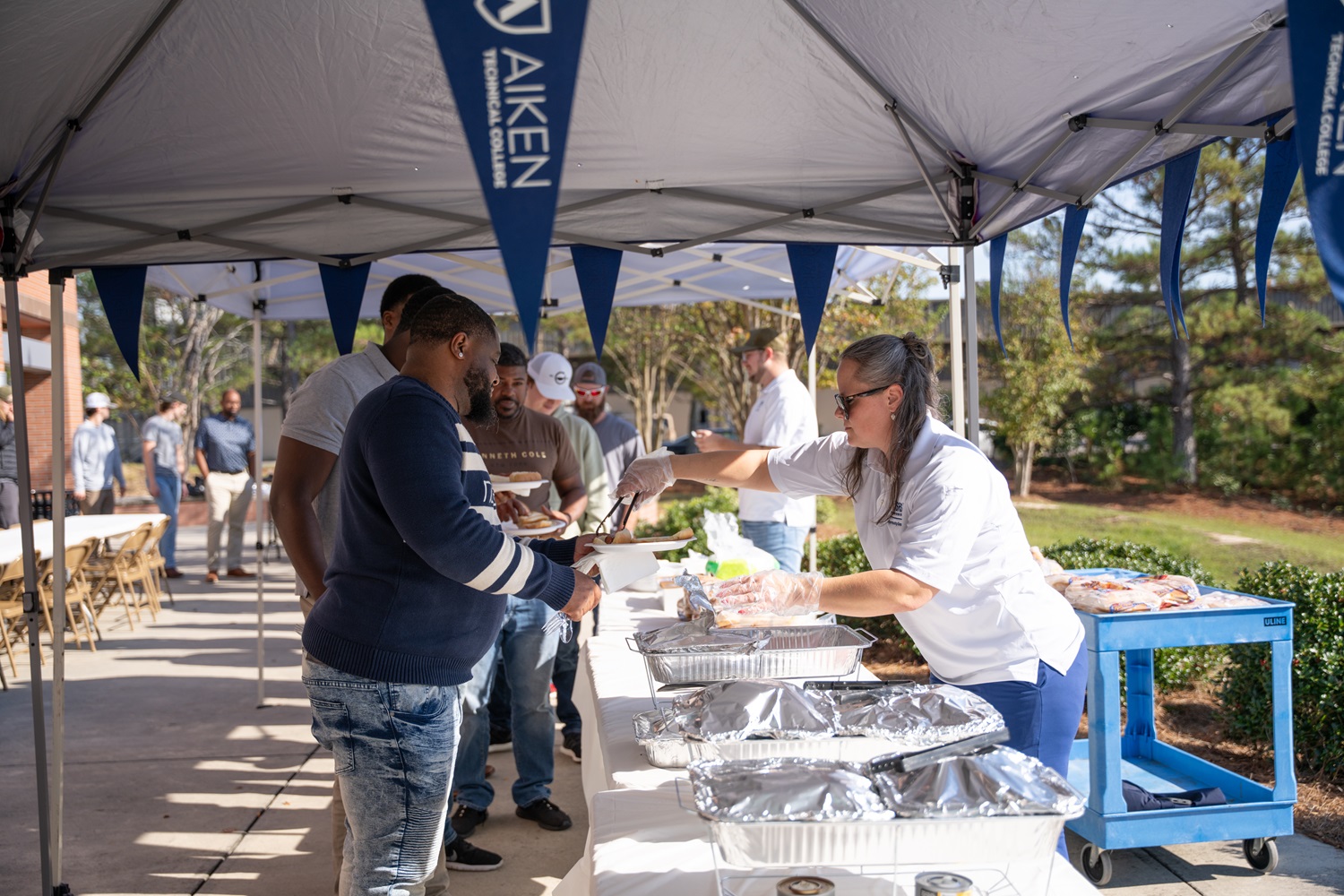 A woman serves food to people on the other side of a table