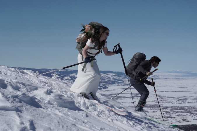 Juan and his wife skiing down a snowy mountain in wedding attire