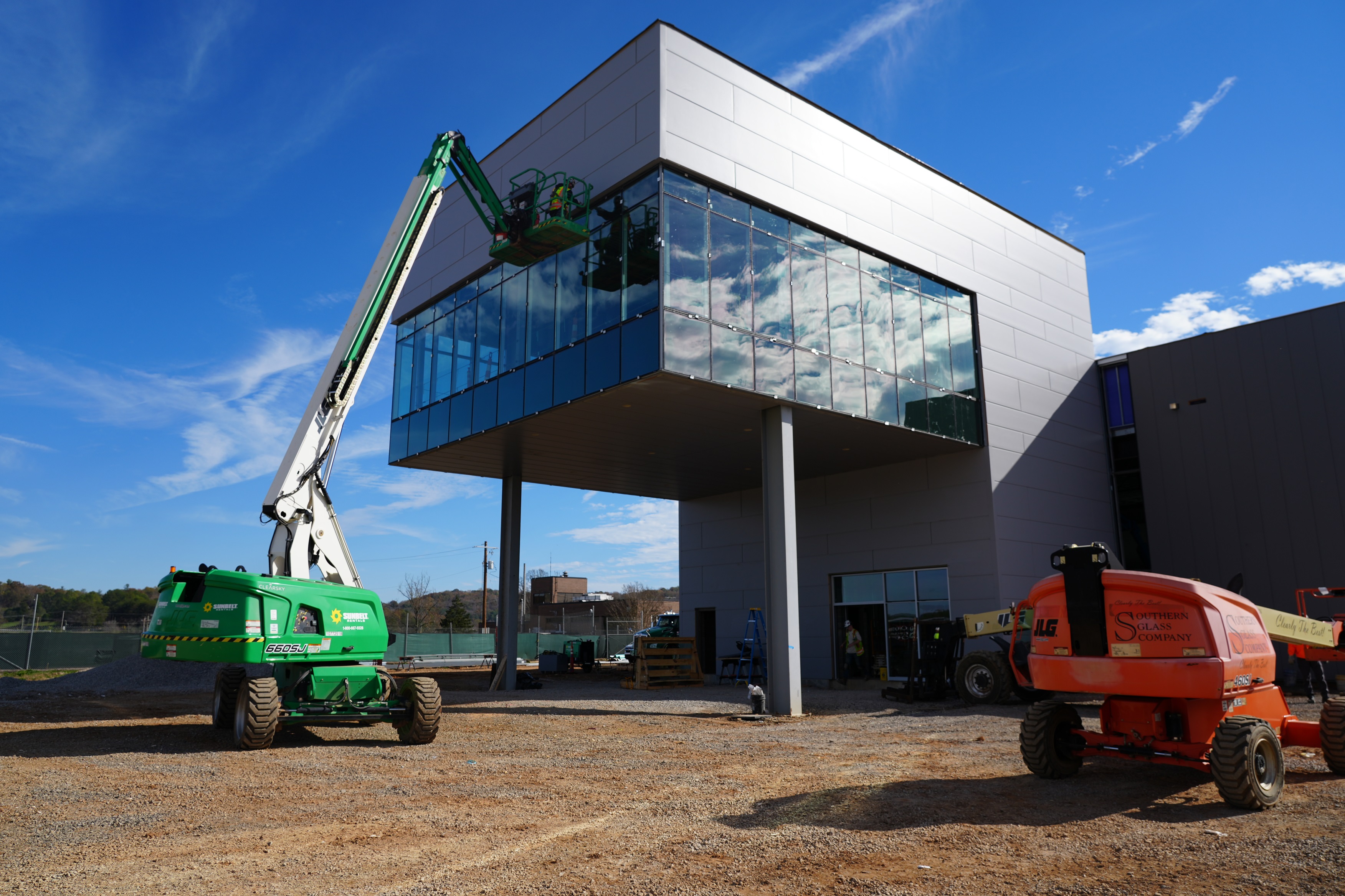 A large grey building with lots of windows, a green crane works on the building