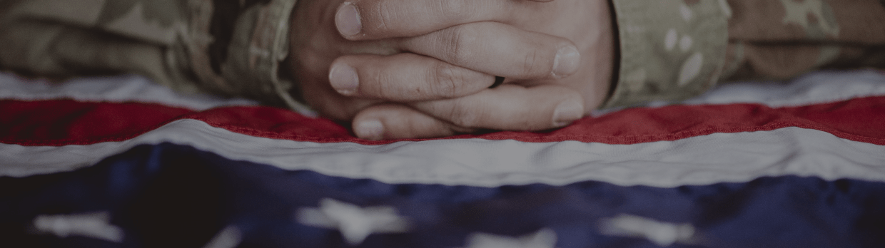 Military mans hand folded on top of American flag