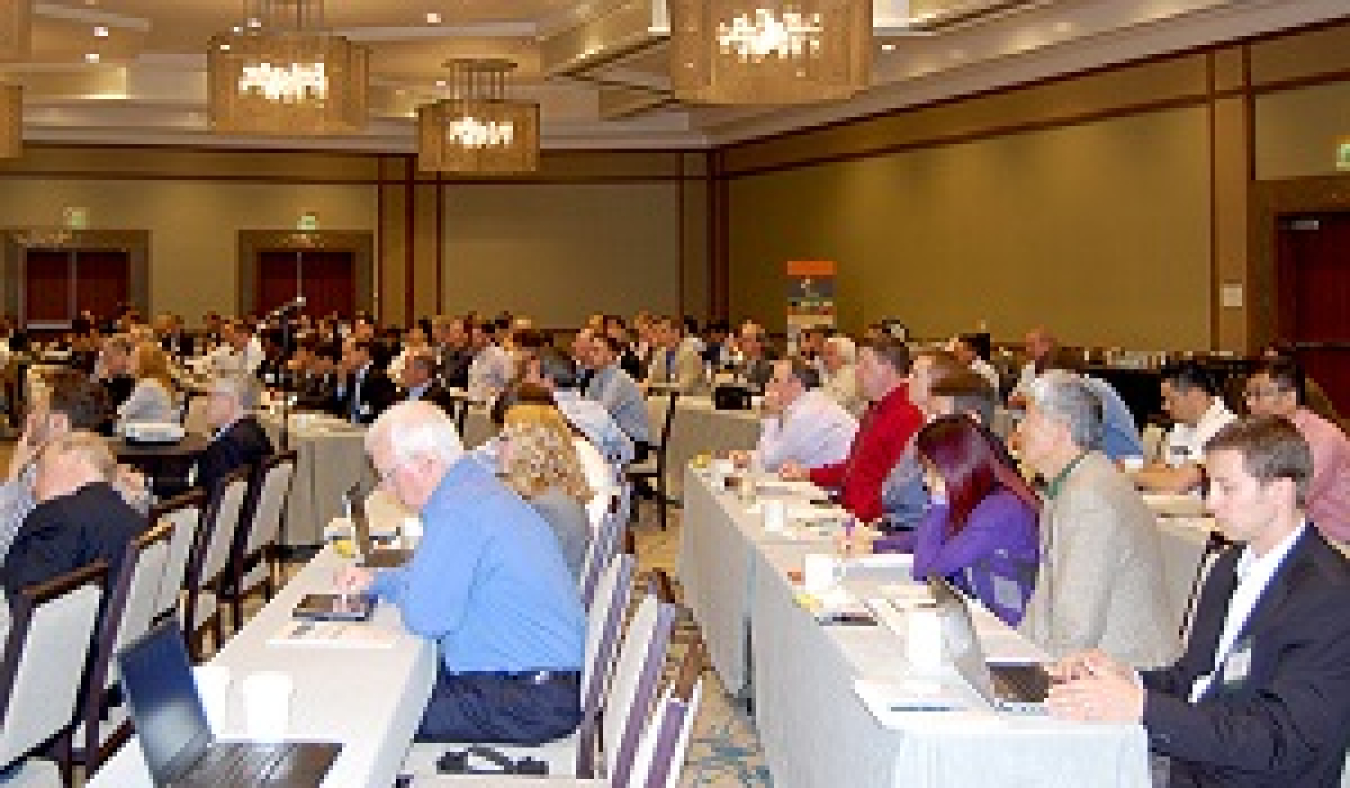 Conference attendees seated at long tables.