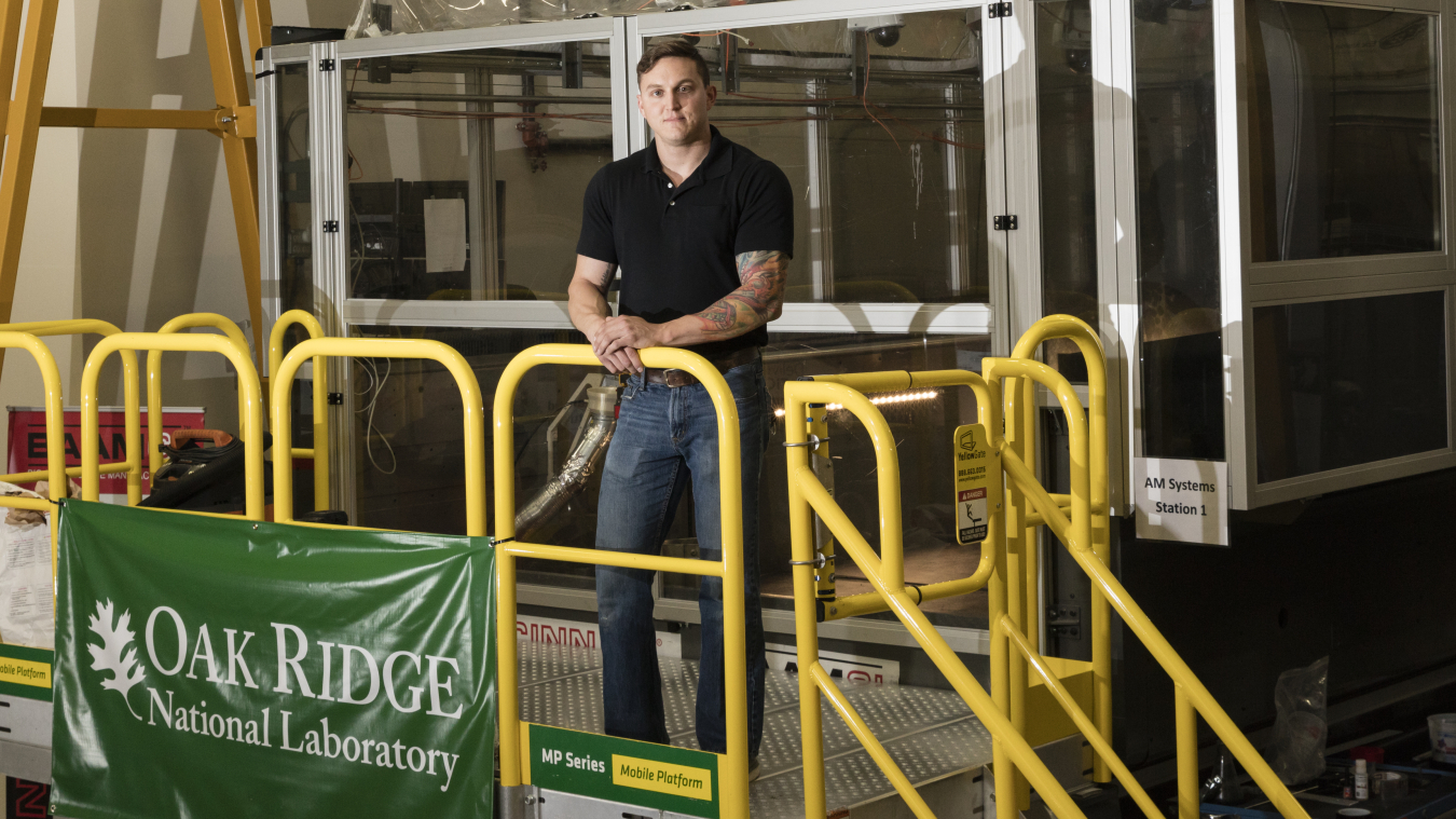 Matt Sallas stands outside of the BAAM machine at Oak Ridge National Laboratory.