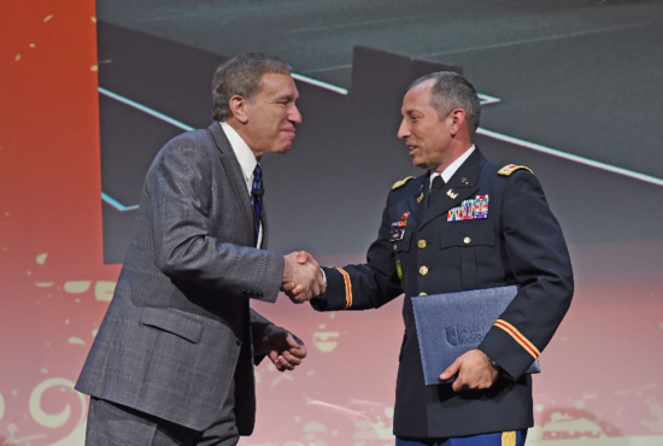 Photo of two men shaking hands at a public event.