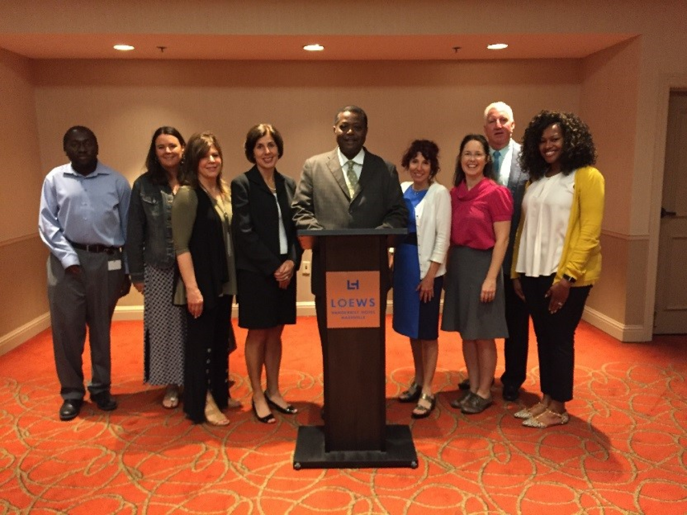 Photo of a group of men and women standing at a lectern.