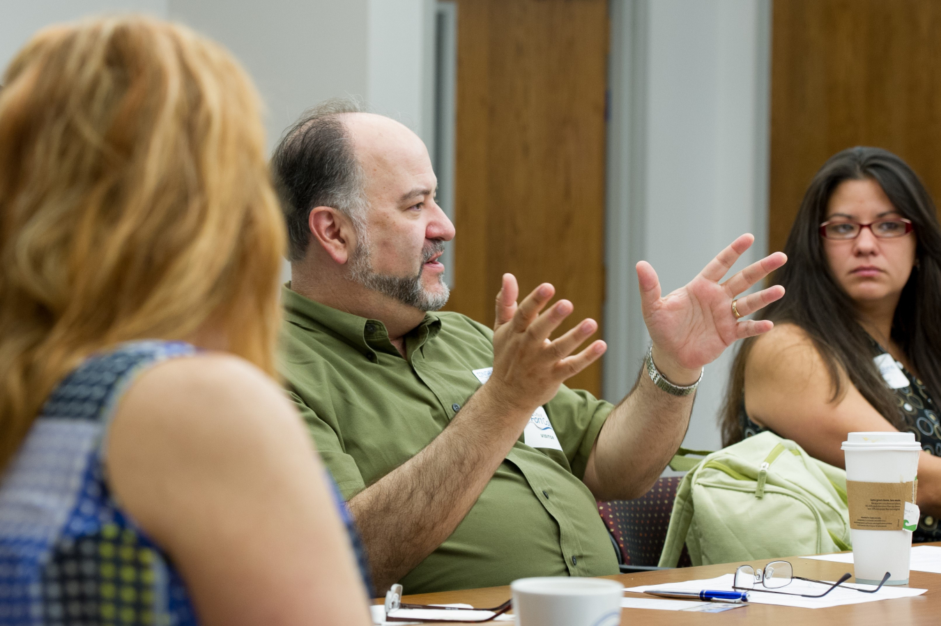 Photo of people at a conference table and a man talking.