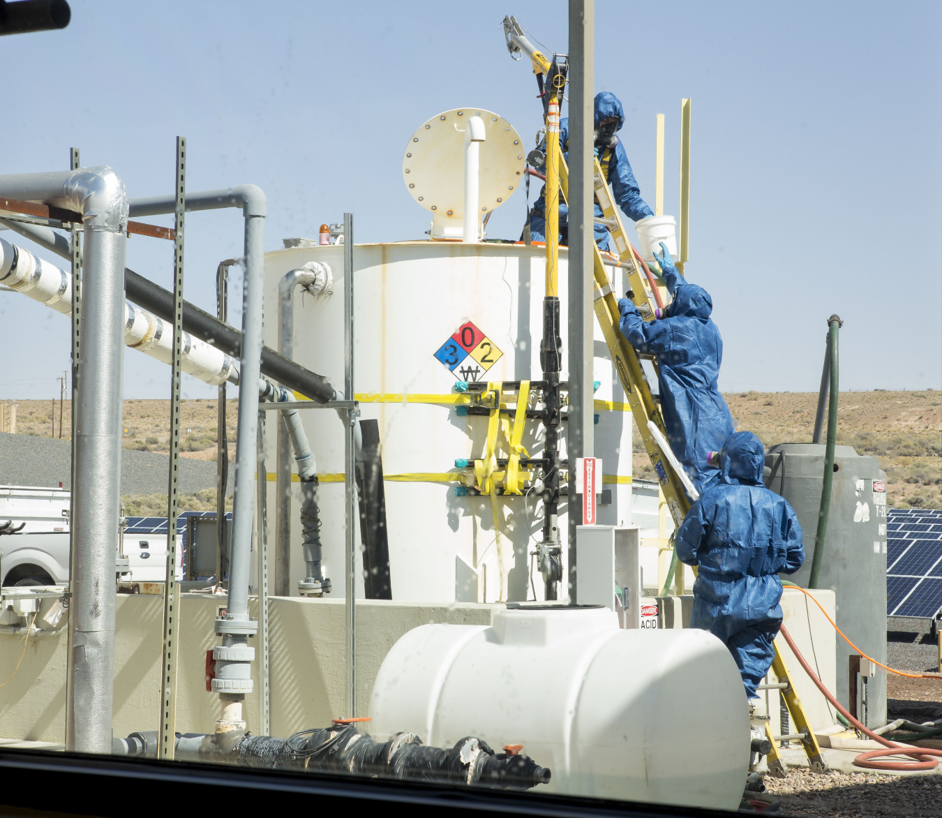 Workers wear personal protective equipment (PPE) while performing acid-neutralization activities.