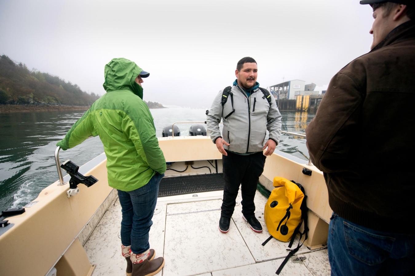 Three people standing on a small boat.