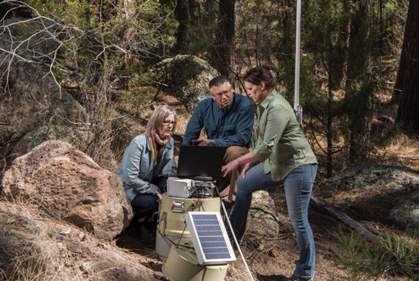 Los Alamos National Laboratory researchers Janette Frigo, Jim Krone and Alex Saari configure a stormwater runoff sensor node in the field.