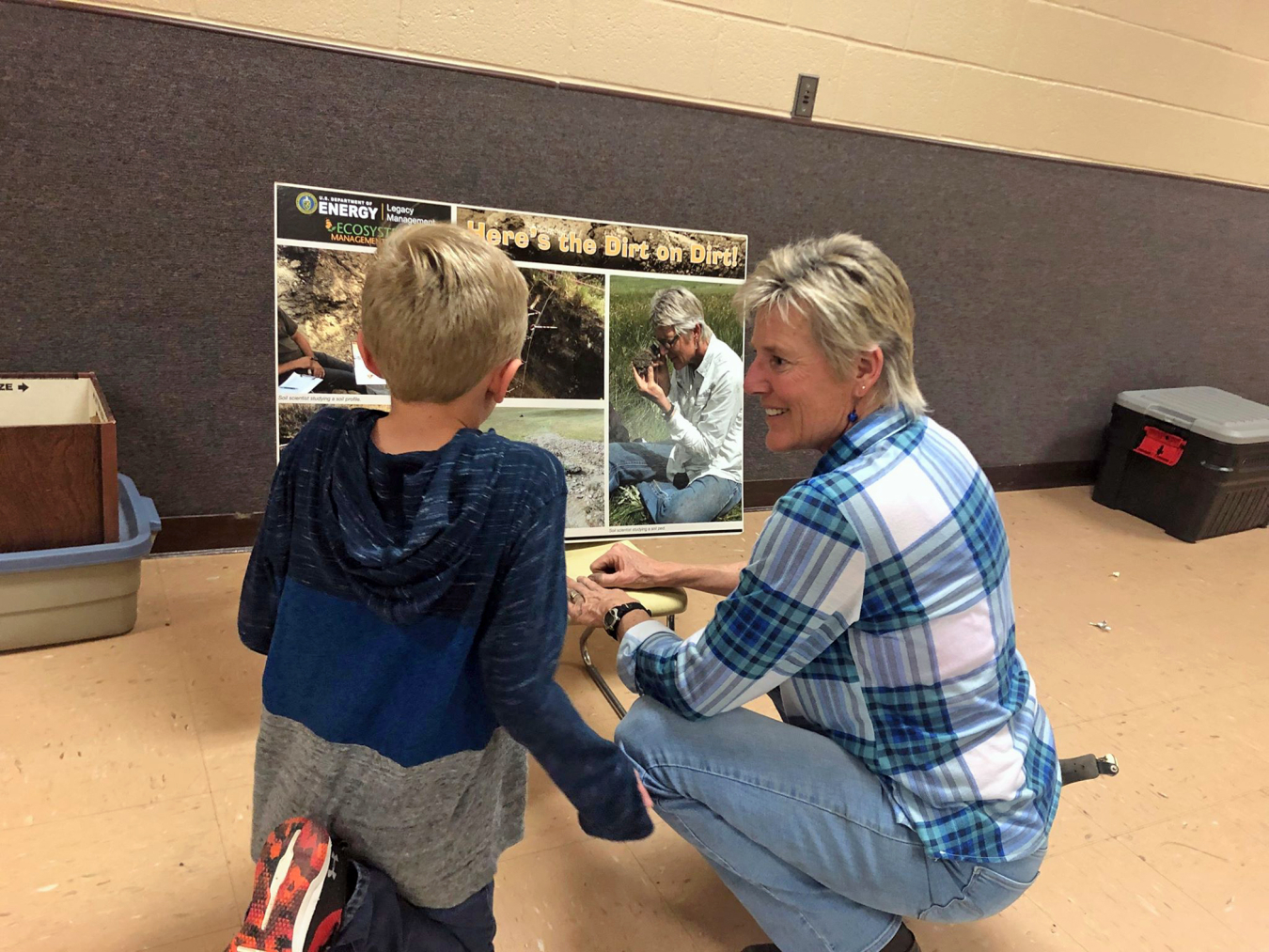 Environmental scientist Marilyn Kastens shares “Here’s the Dirt on Dirt!” poster with a student.