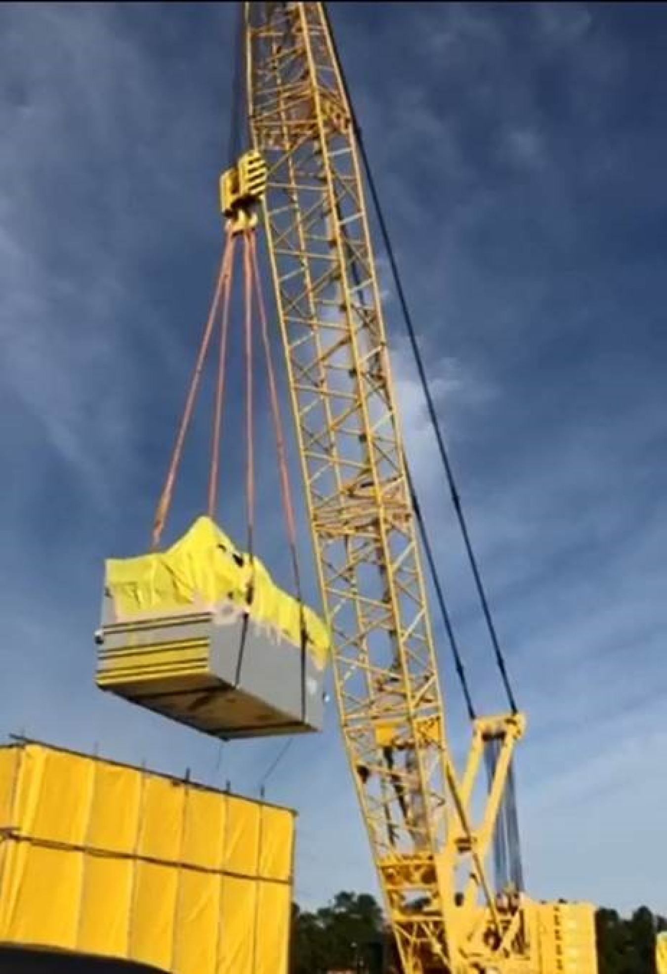 A crane lifts the High Activity Waste Tank Trailer from containment into a railcar.