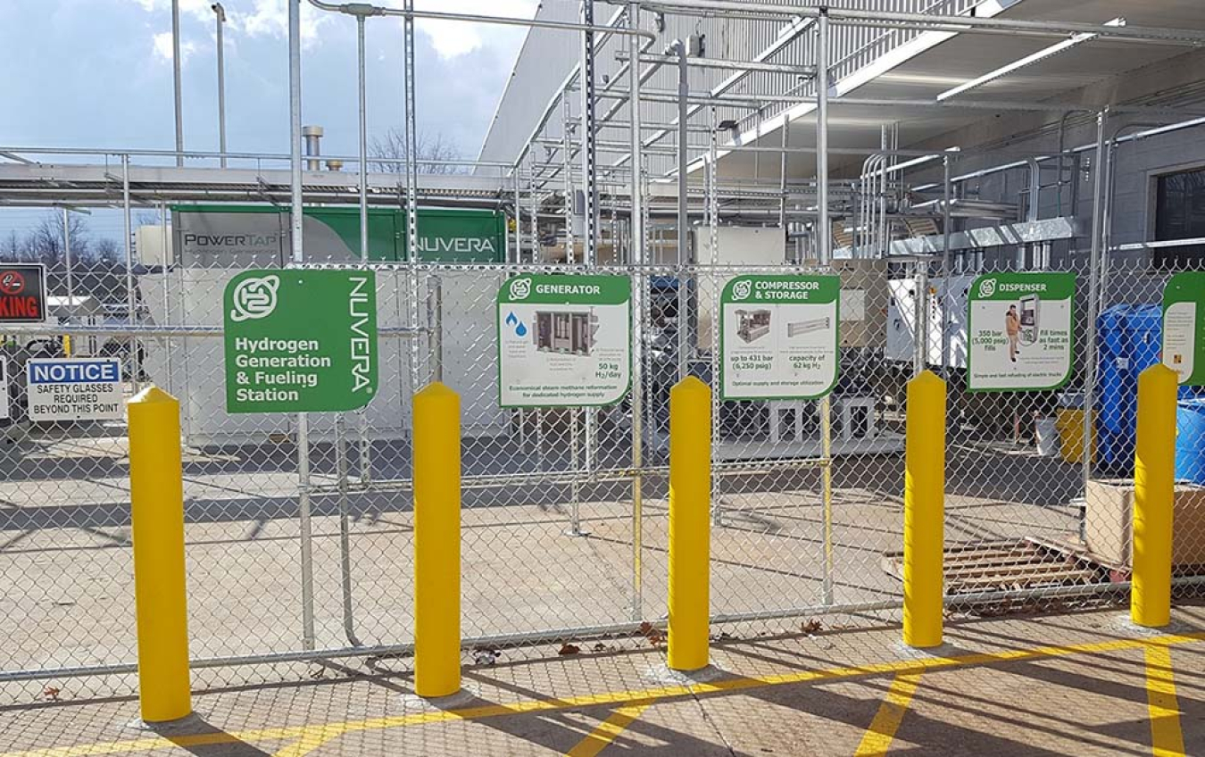 A fence with four signs explaining the Hydrogen Generation and Fueling Station.