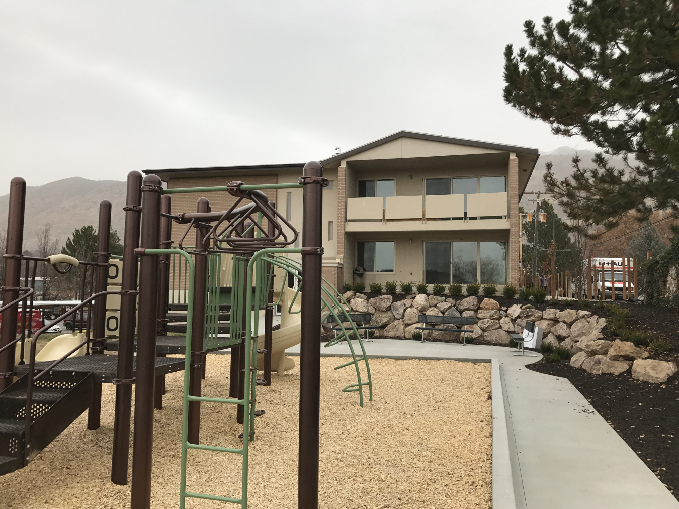 Apartment building exterior in the background, with children's playground equipment in the foreground.