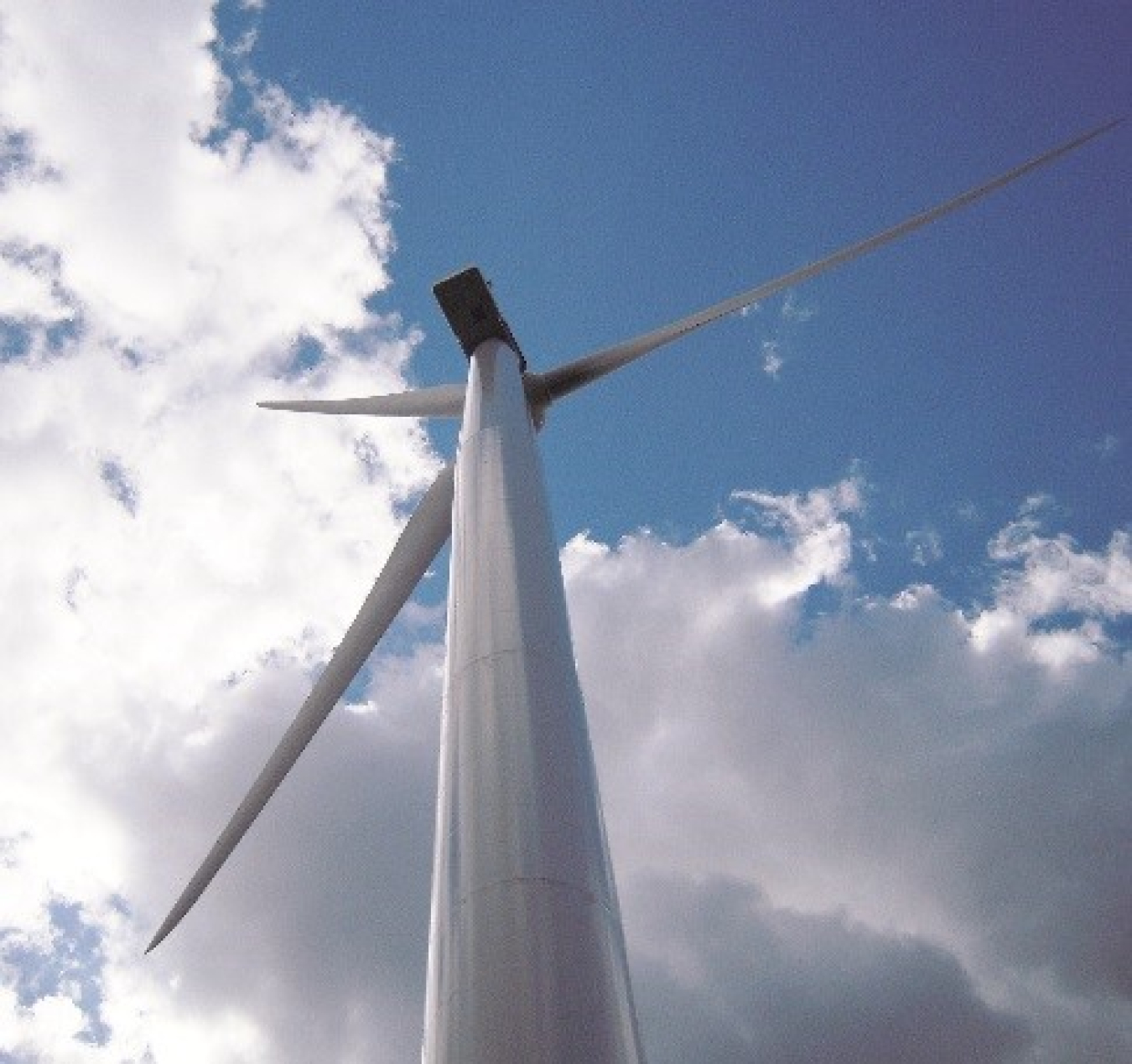 wind turbine from below against a blue sky and clouds.