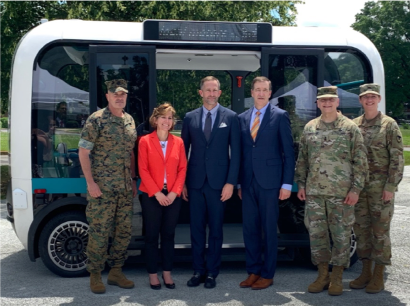 Six people standing in front of an autonomous vehicle.