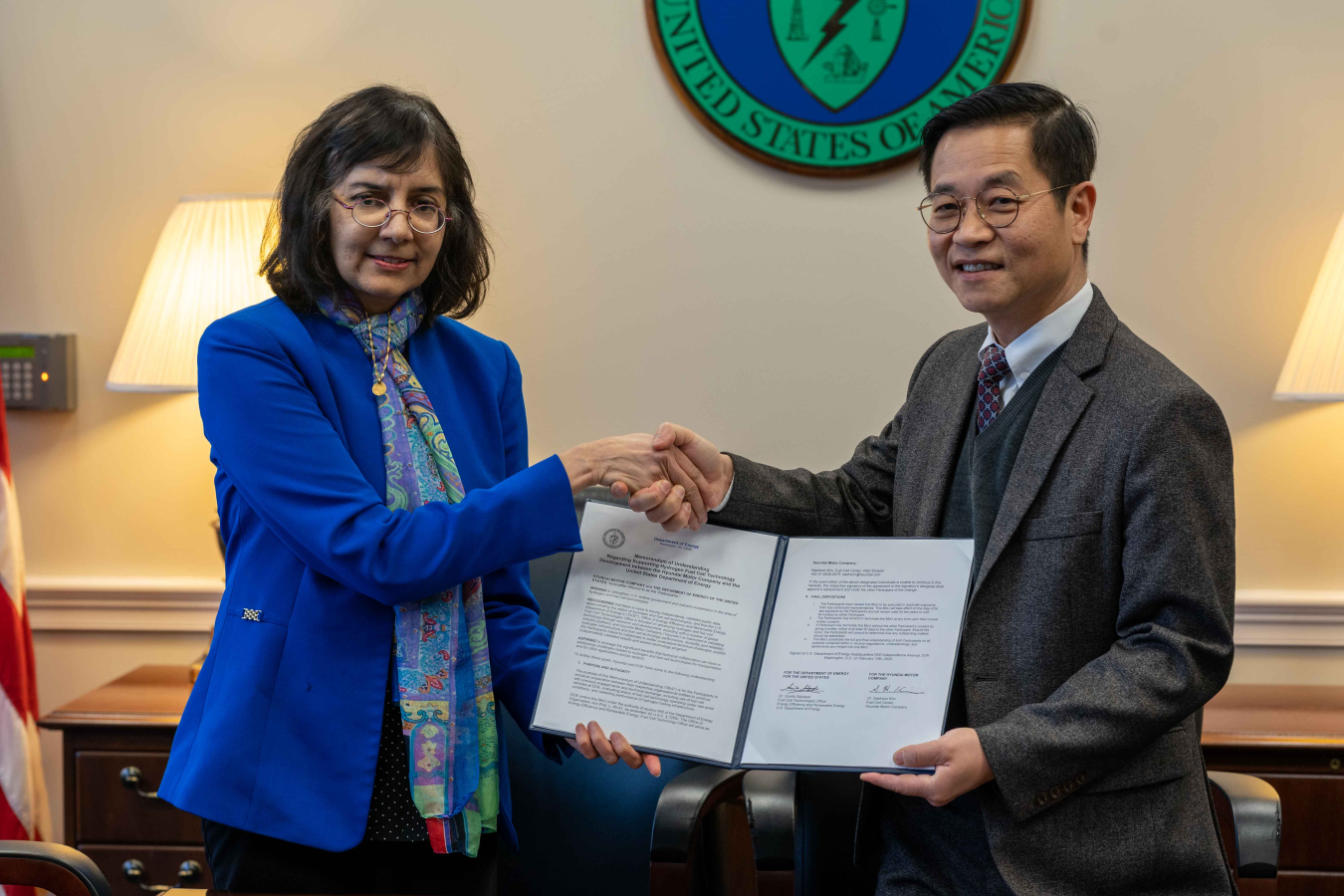 Hydrogen and Fuel Cells Program Director Sunita Satyapal shakes hands with a Hyundai representative while holding a signed Memorandum of Understanding.