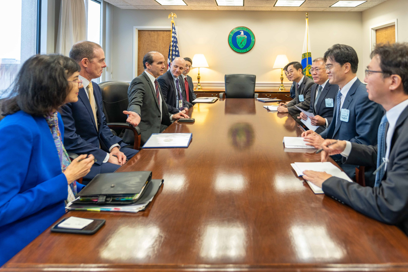 Ten representatives from DOE and Hyundai sit around a conference room table.