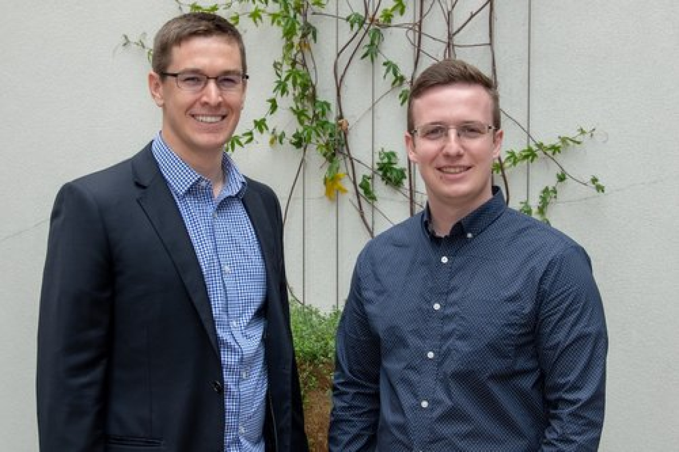 Two men in business attire shown from the waist up, side by side looking at the camera.