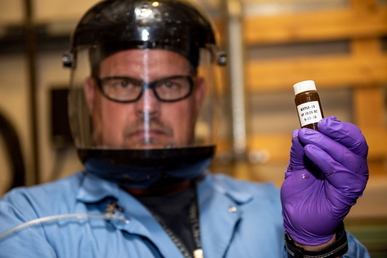 a photo of a scientist holding up a small glas bottle.