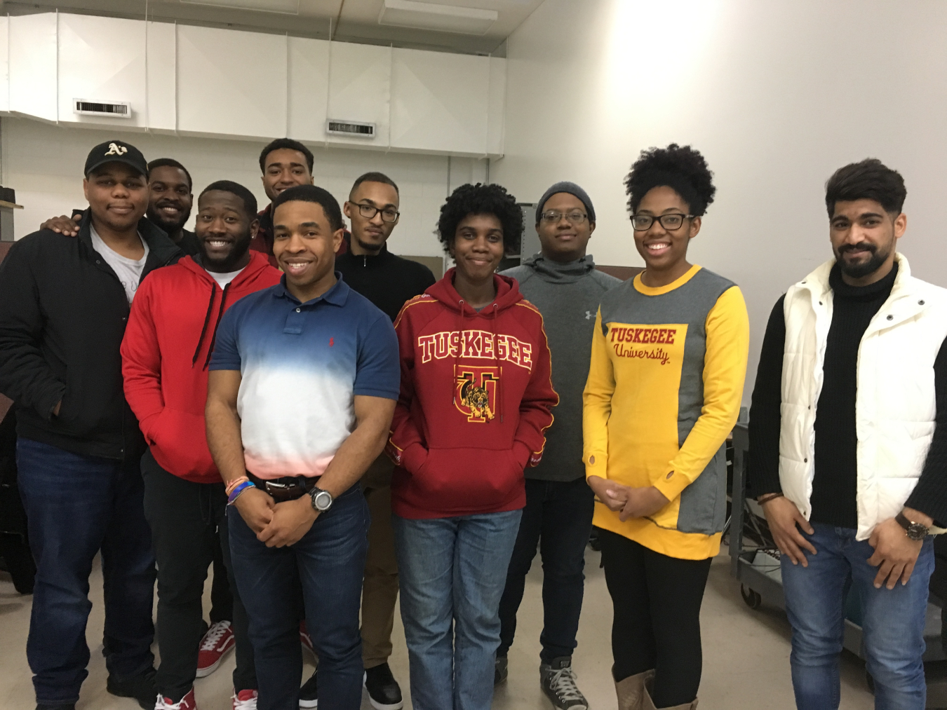 A group of young people stand together smiling. 