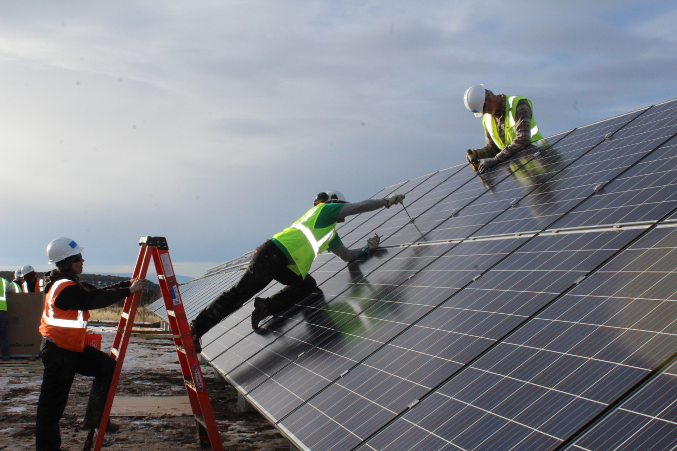 Three workers installing solar photovoltaic panels