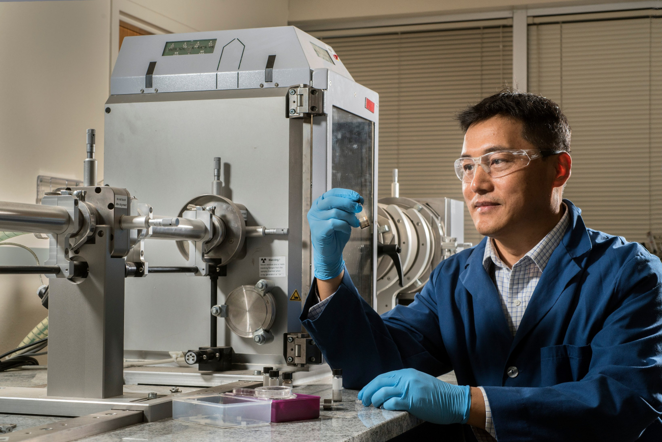 Sandia National Laboratories researcher Hongyou Fan holds a container enclosing gold supercrystals in front of a small-angle X-ray scattering instrument. Binary Solvent Diffusion for Fabrication of Large Nanoparticle Supercrystals won an R&D Award.