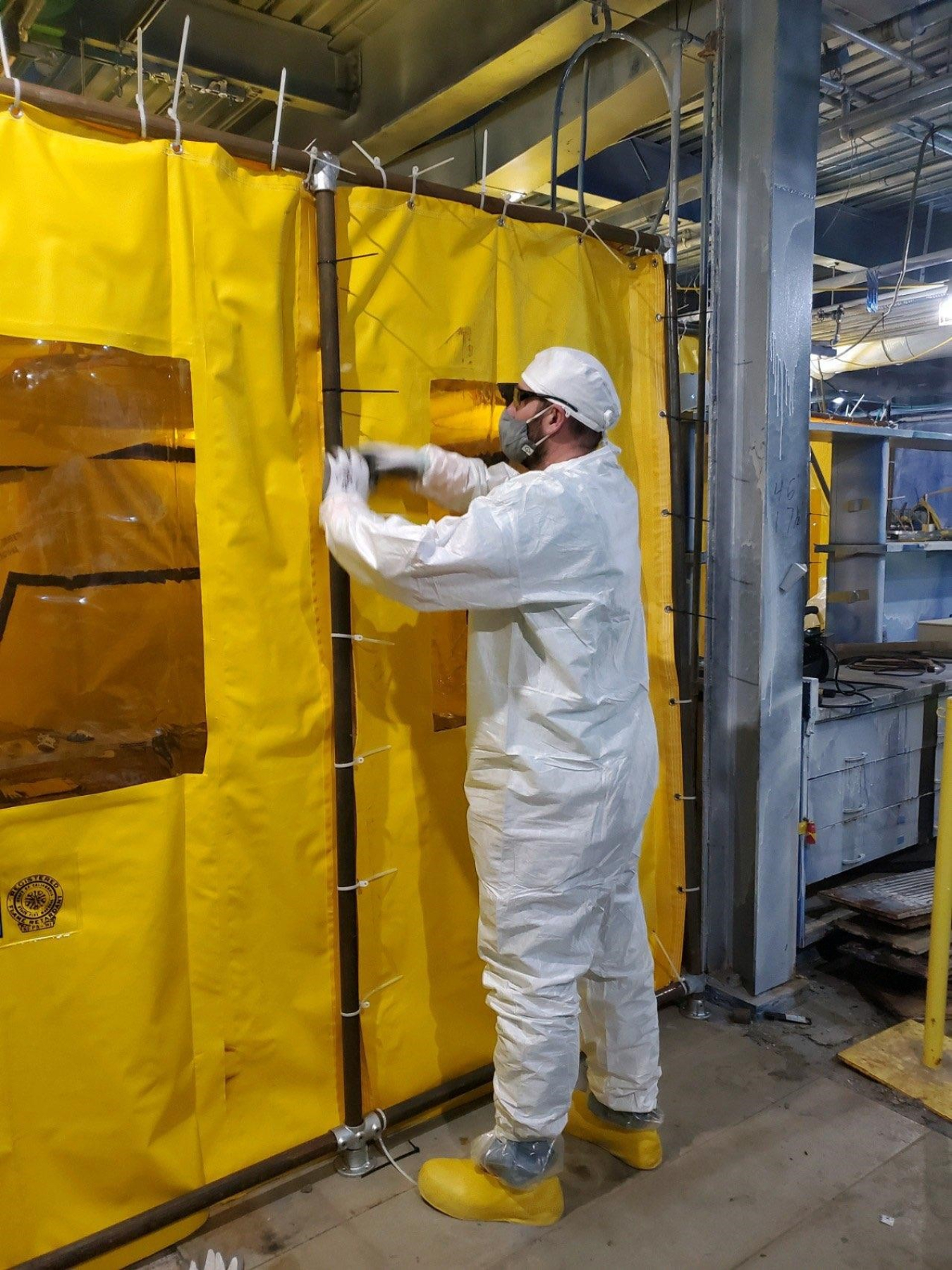 Jim Kuhn, Jr., an employee with CH2M HILL BWXT West Valley, helps set up a protective tent above the Vent Wash Room in the Main Plant Process Building to support ductwork cutting as the site prepares for the future demolition of the facility at the West Valley Demonstration Project.