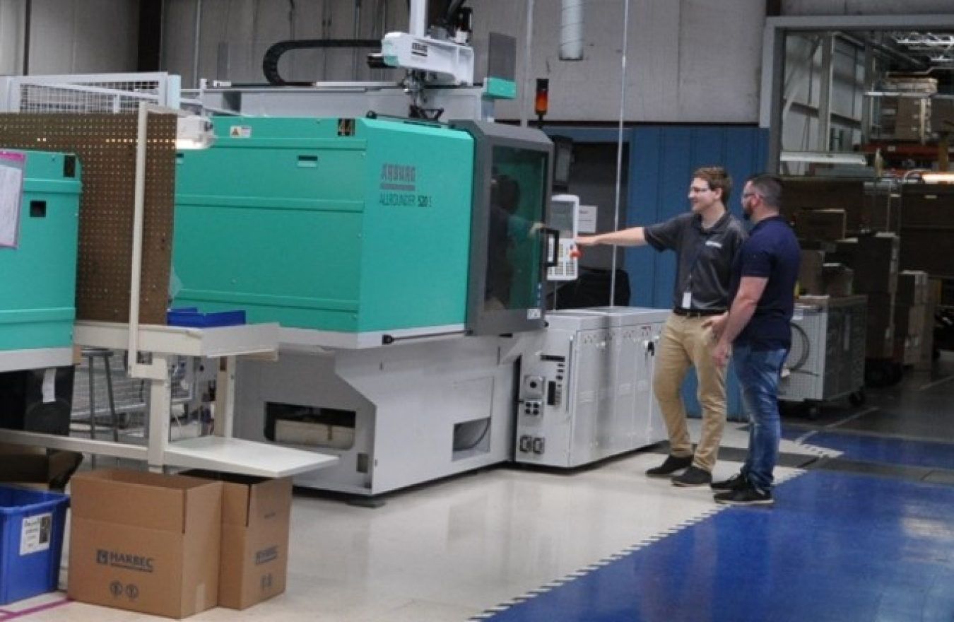 Two men standing in front of machinery.