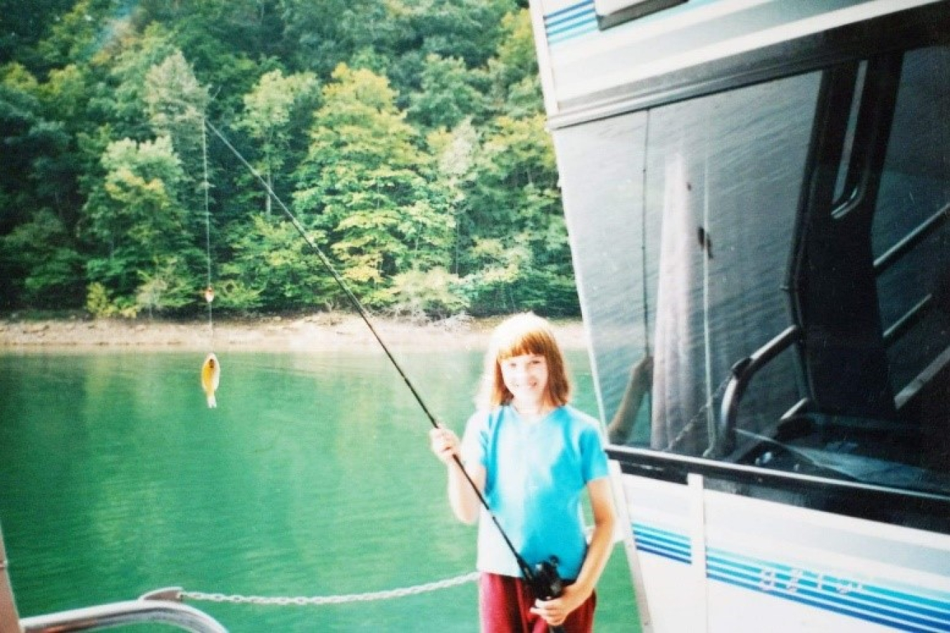 A girl smiling with a fishing pole.