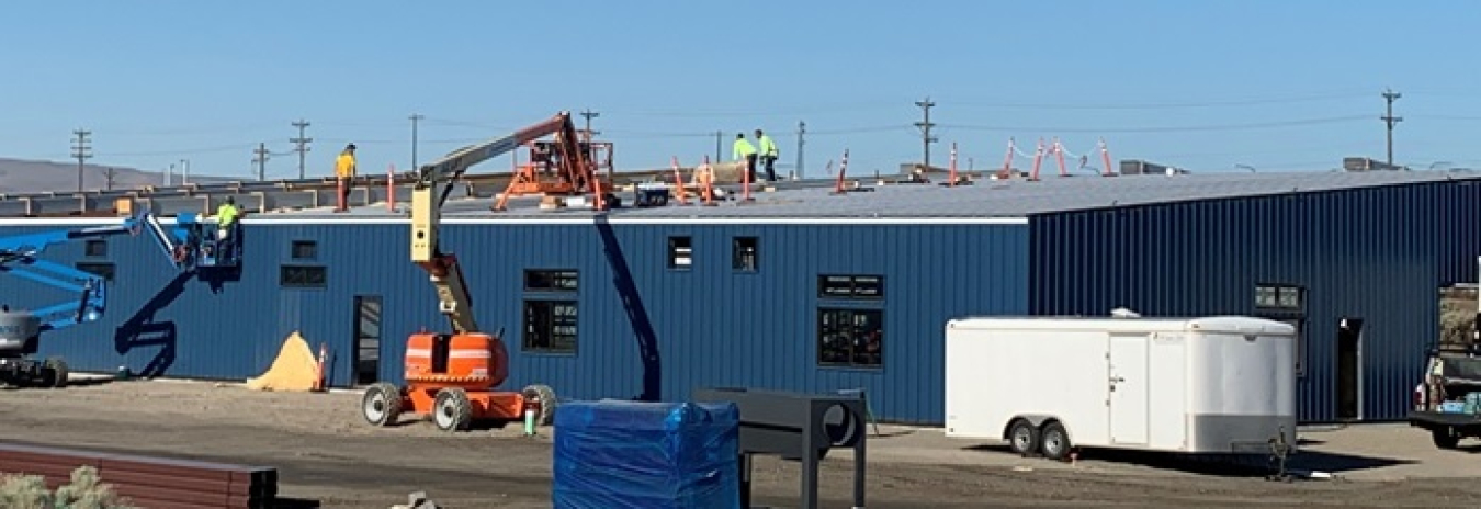 Workers with EM tank operations contractor Washington River Protection Solutions install roofing on a new, centralized facility for craft personnel assigned to tank operations and maintenance at the Hanford Site. The facility is scheduled for completion in early 2022. 