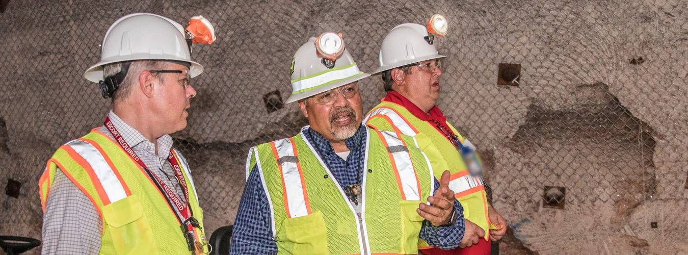 Ed Garza, center, assistant manager at EM’s Carlsbad Field Office (CBFO), explains current operations in the Waste Isolation Pilot Plant underground to EM Acting Assistant Secretary William "Ike" White. CBFO Manager Reinhard Knerr is behind Garza.