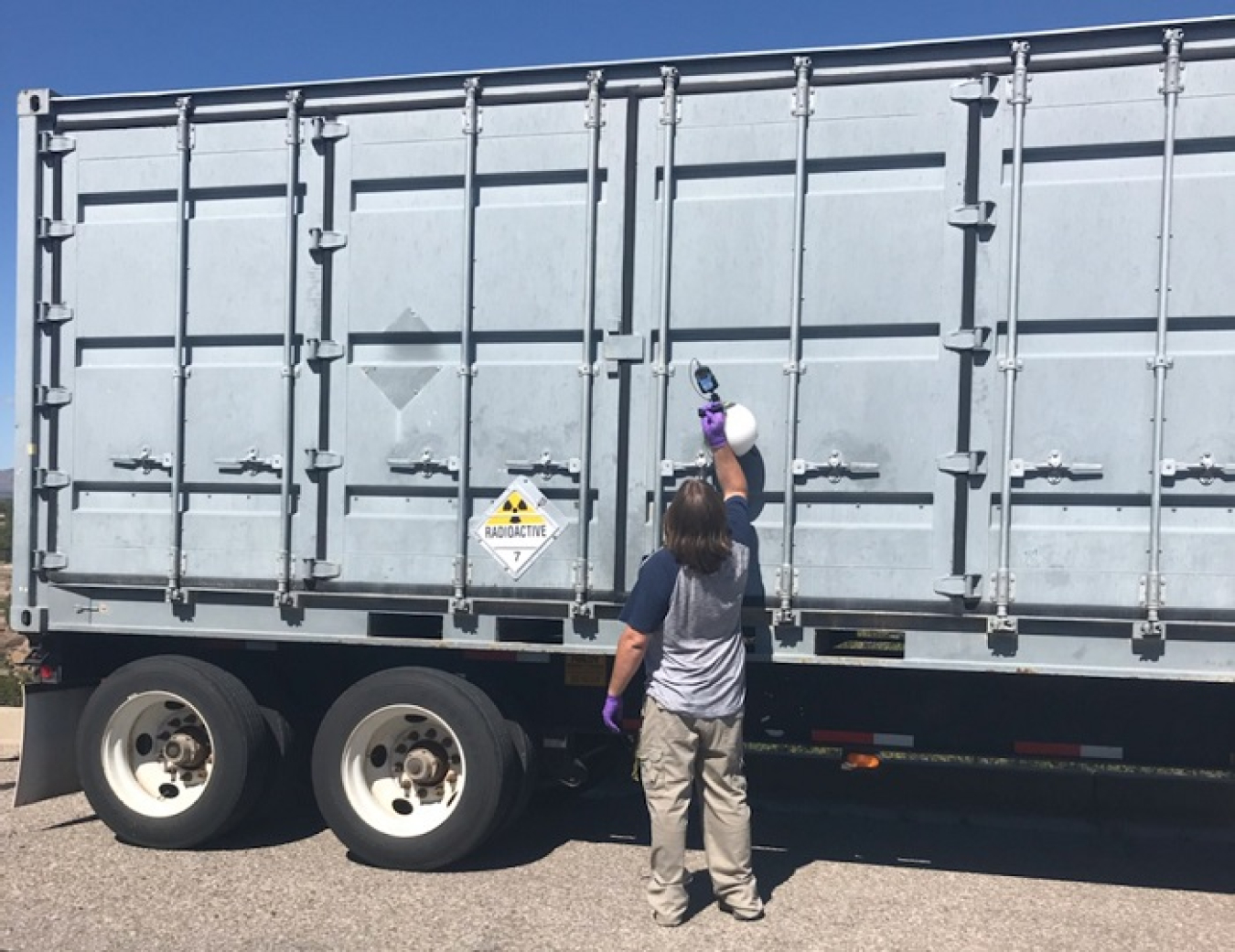 A worker with Newport News Nuclear BWXT-Los Alamos, the cleanup contractor for the EM Los Alamos Field Office (EM-LA), surveys EM-LA's 30th transuranic waste shipment of fiscal 2021 in Area G at Technical Area 54.