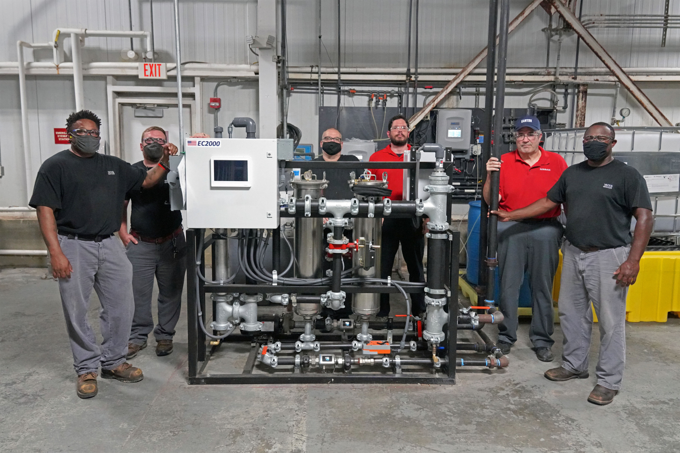 several people standing in a manufacturing facility