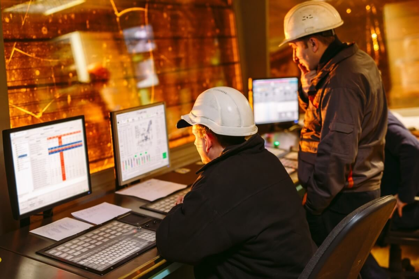 Two men in hardhats looking at data on a computer.