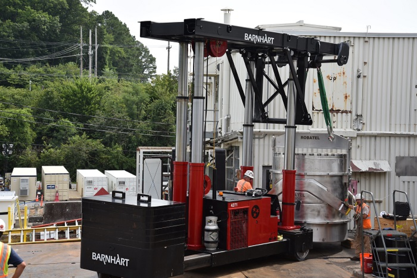 Workers use specialized equipment to move and lift an 88,000-pound transportation cask onto a trailer to ship it for off-site disposal.