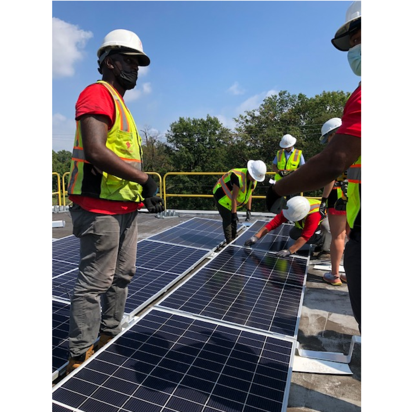 Team members work together to install solar panels in the community solar array on the rooftop of Crescent Park Village.