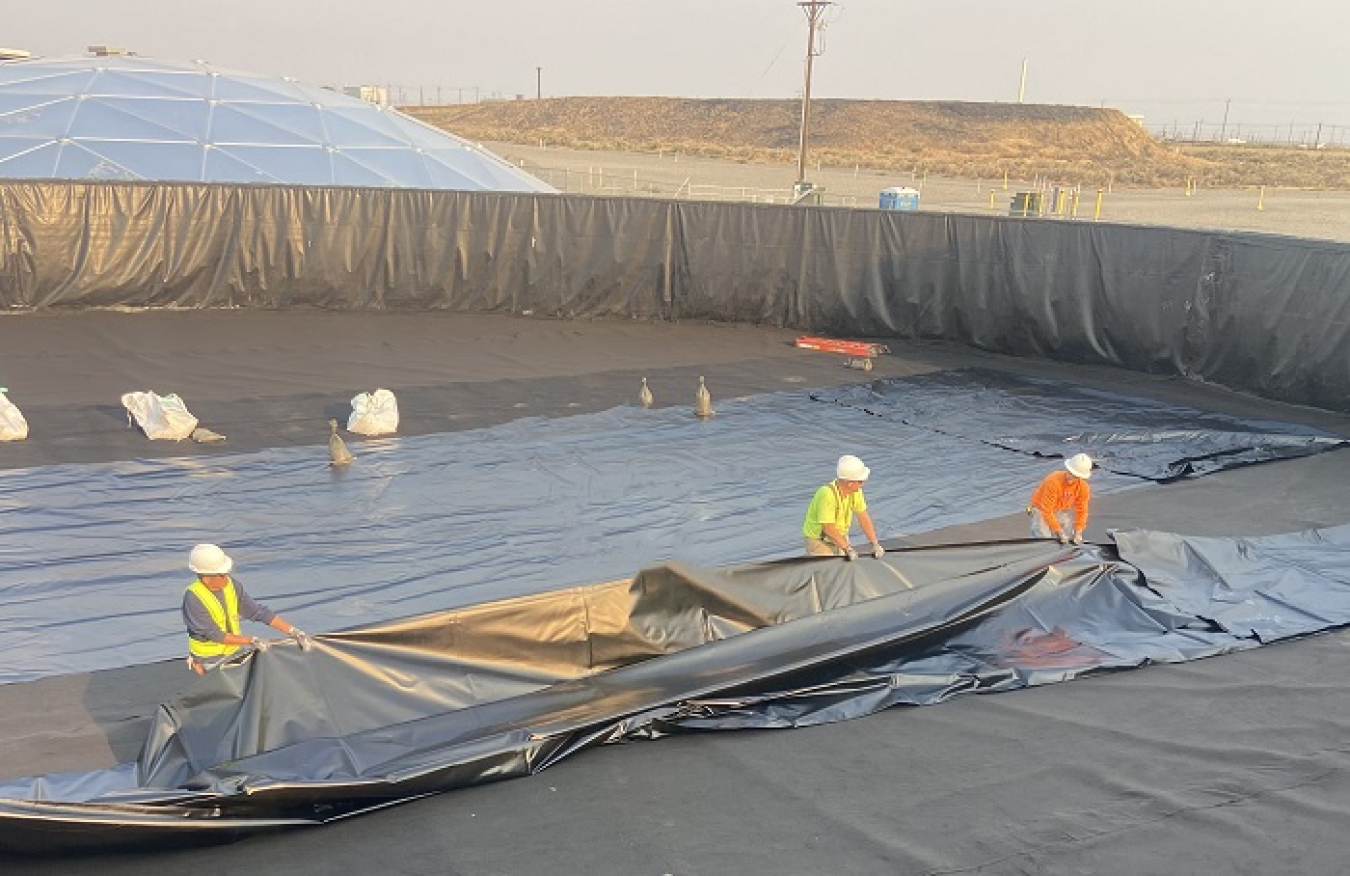 Workers with EM contractor Central Plateau Cleanup Company are installing heavy-duty liners inside two 400,000-gallon leachate tanks at the Integrated Disposal Facility at the Hanford Site. The tanks contain leachate — water from rain, snowmelt, and dust suppression — until it is transferred to an on-site water treatment facility.