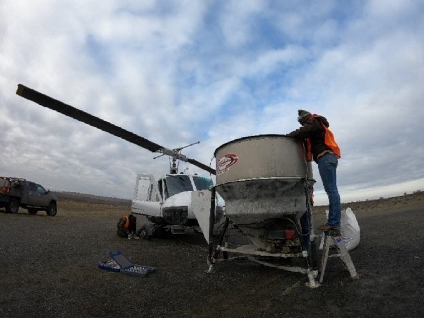 Workers ready a hanging bucket for a helicopter used to drop native grass and shrub seed on the Hanford Site after a fire destroyed 5,500 acres of critical habitat in June 2020.