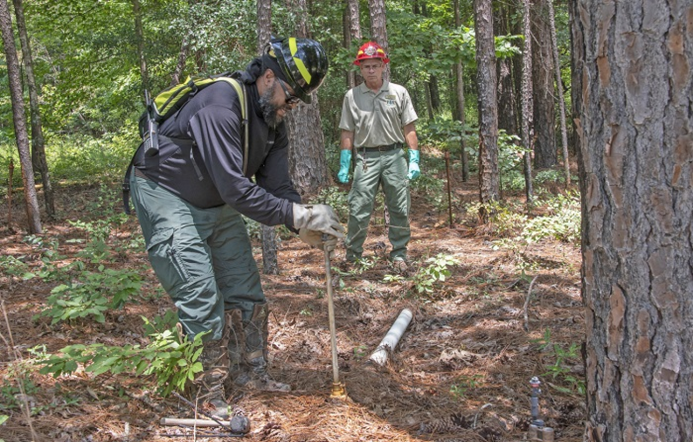 At EM’s Savannah River Site, U.S. Forest Service employees Secunda Hughes, left, a civil engineering technician, and Andrew Thompson, a forester, inspect irrigation piping and sprinkler heads, part of a 62-acre pine plantation used to safely disperse tritium into the atmosphere and away from local waterways. 